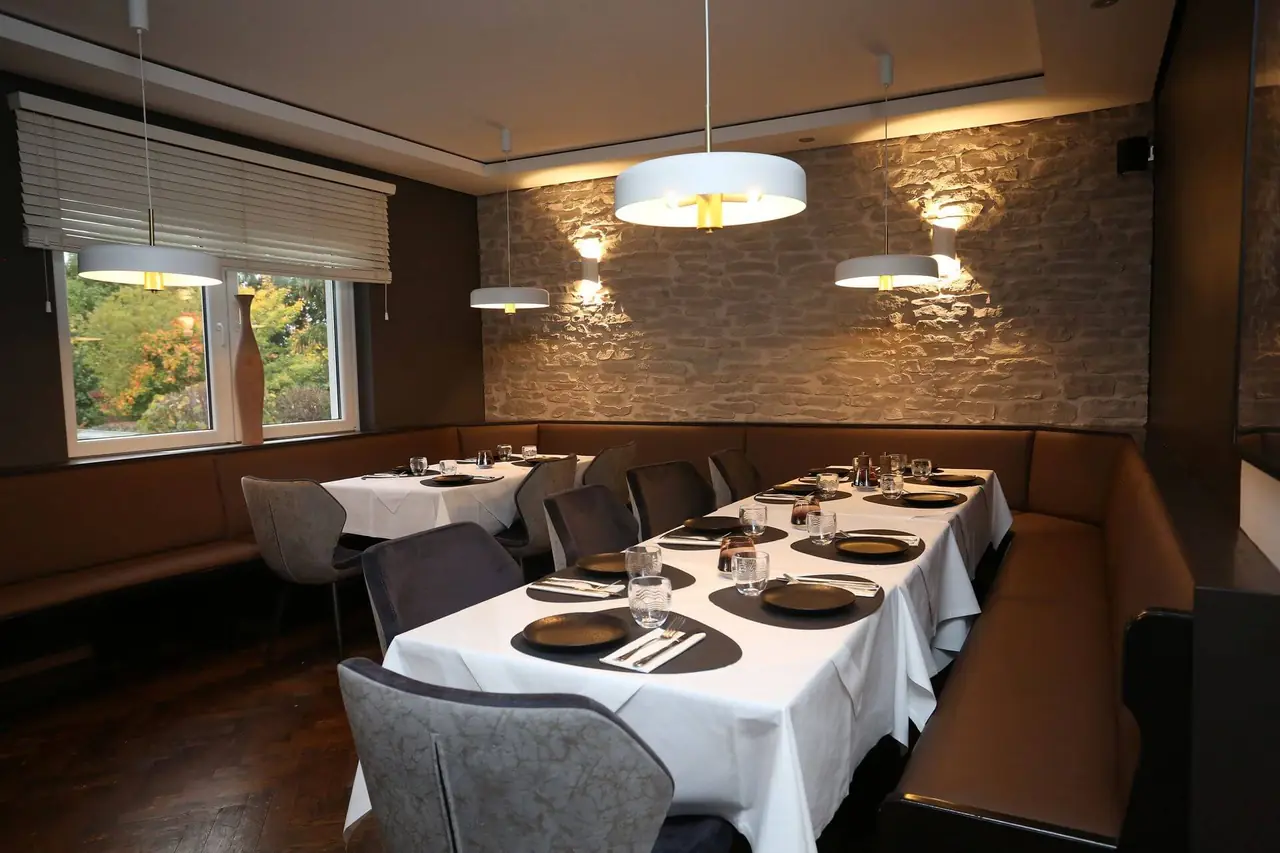 Gedeckte Tische vor der beleuchteten Steinwand im Cocco Pazzo
